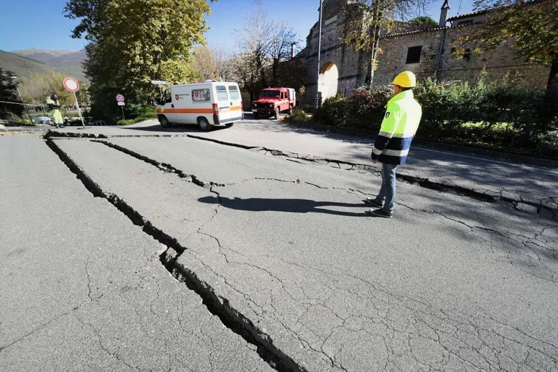 A paved street split open by an earthquake, with a wide crack running its length